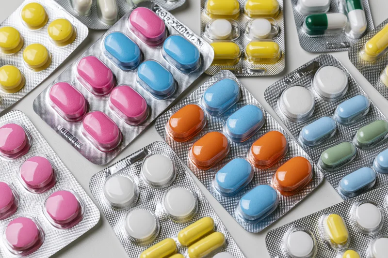 Assorted pharmaceutical blister packs with colorful pills arranged on a white surface