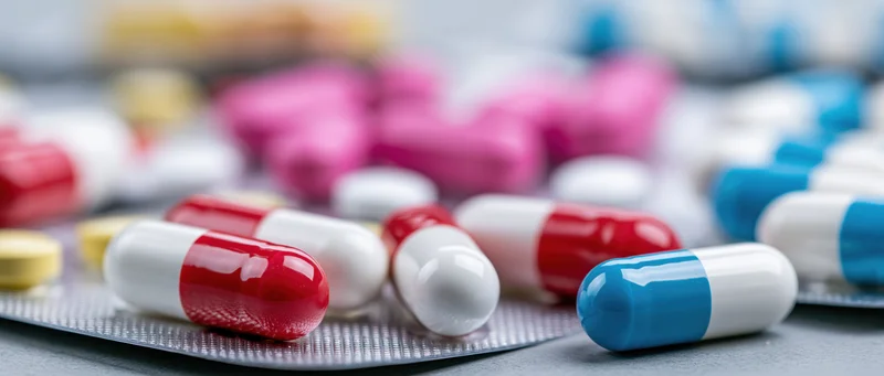 Colorful pharmaceutical capsules and tablets scattered on a blister pack surface