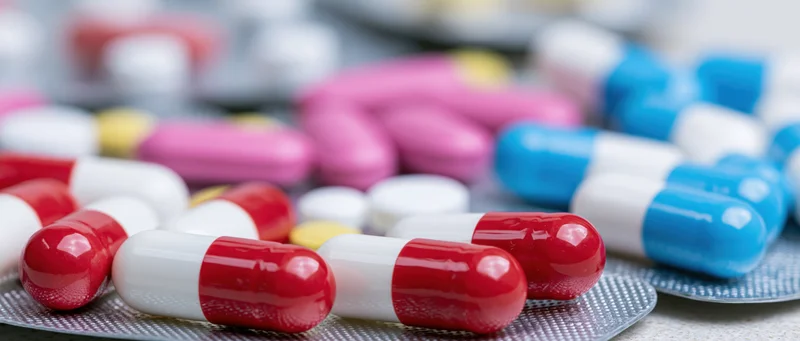 Colorful pharmaceutical capsules and tablets scattered on a blister pack surface