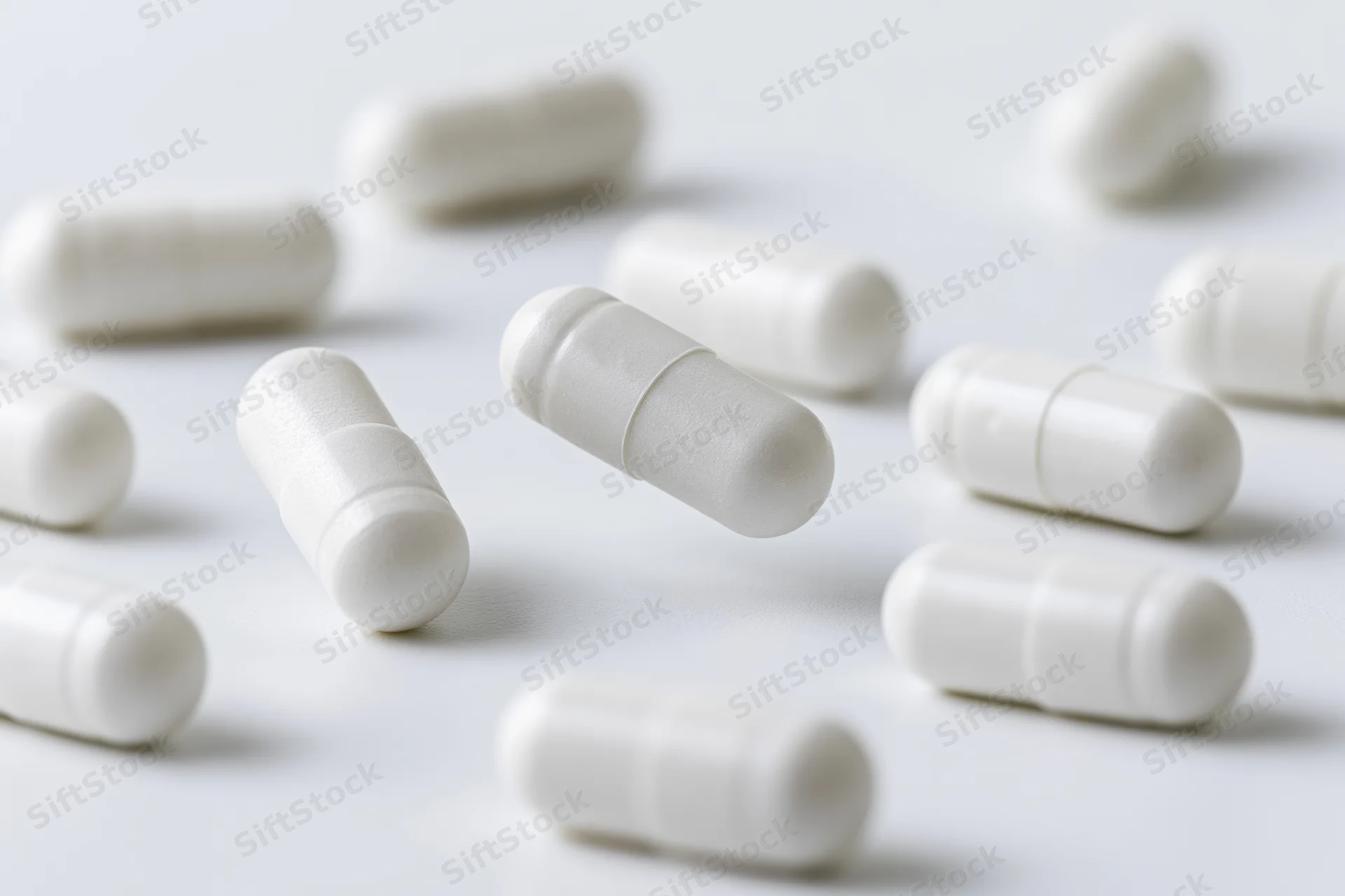 White pharmaceutical capsules scattered on a plain surface