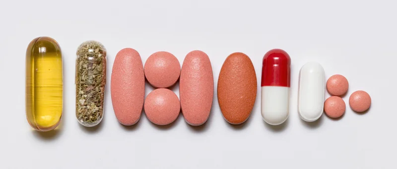 Assorted supplements and capsules arranged in a row on white background