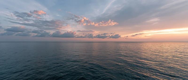 Calm ocean surface reflecting sunset sky at twilight