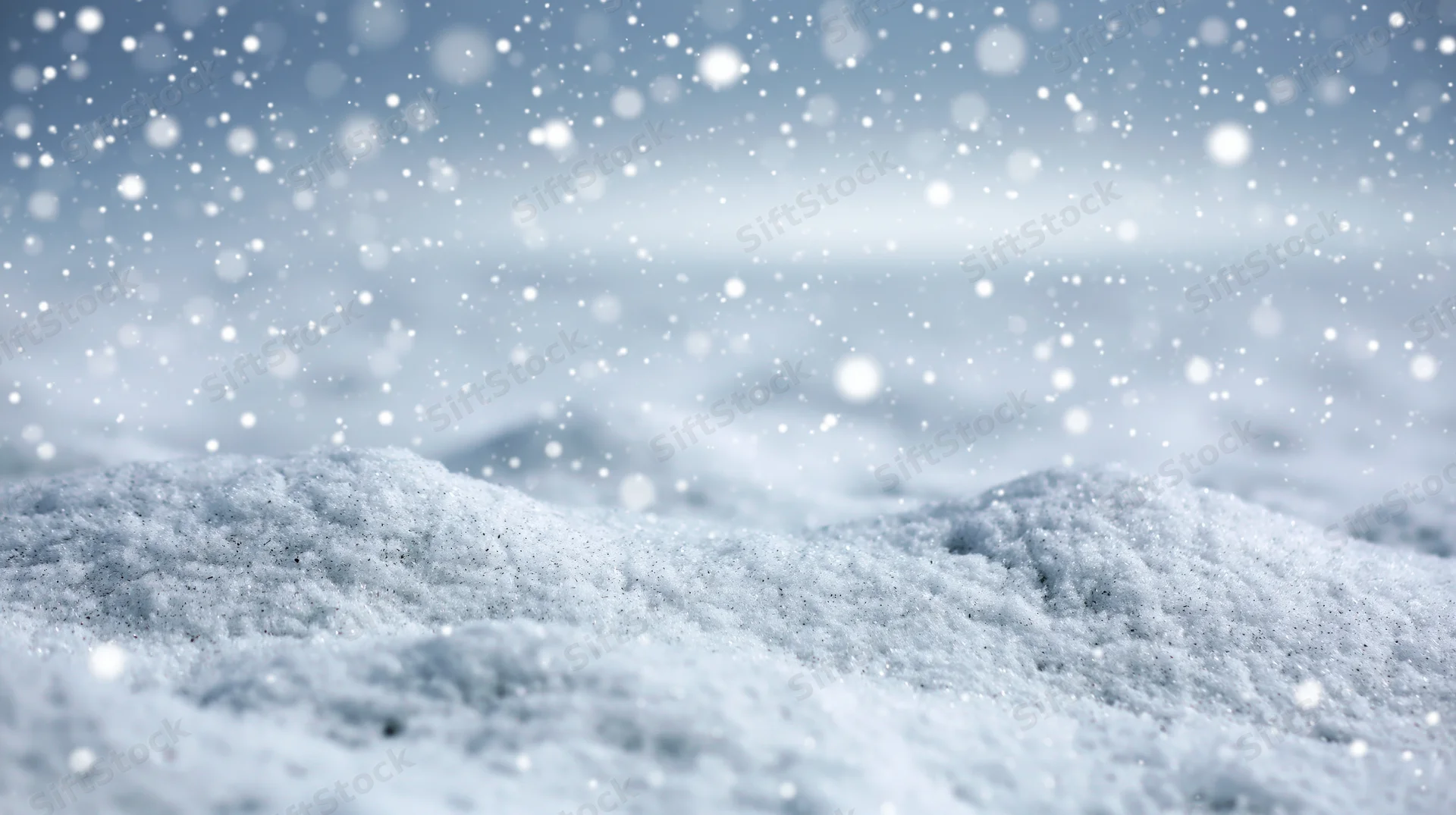 Snowy landscape with falling snowflakes and snowdrifts under overcast sky
