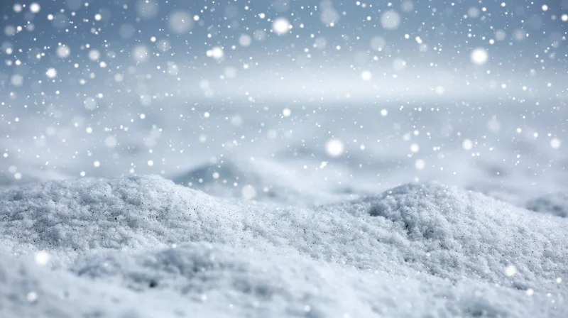 Snowy landscape with falling snowflakes and snowdrifts under overcast sky