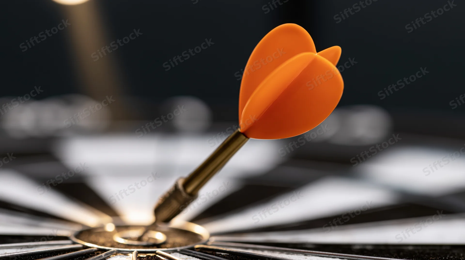 Orange dart with metallic barrel stuck dead-center in a black and white dartboard