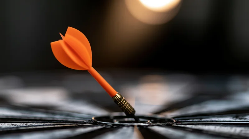 Orange dart stuck dead-center in a black target