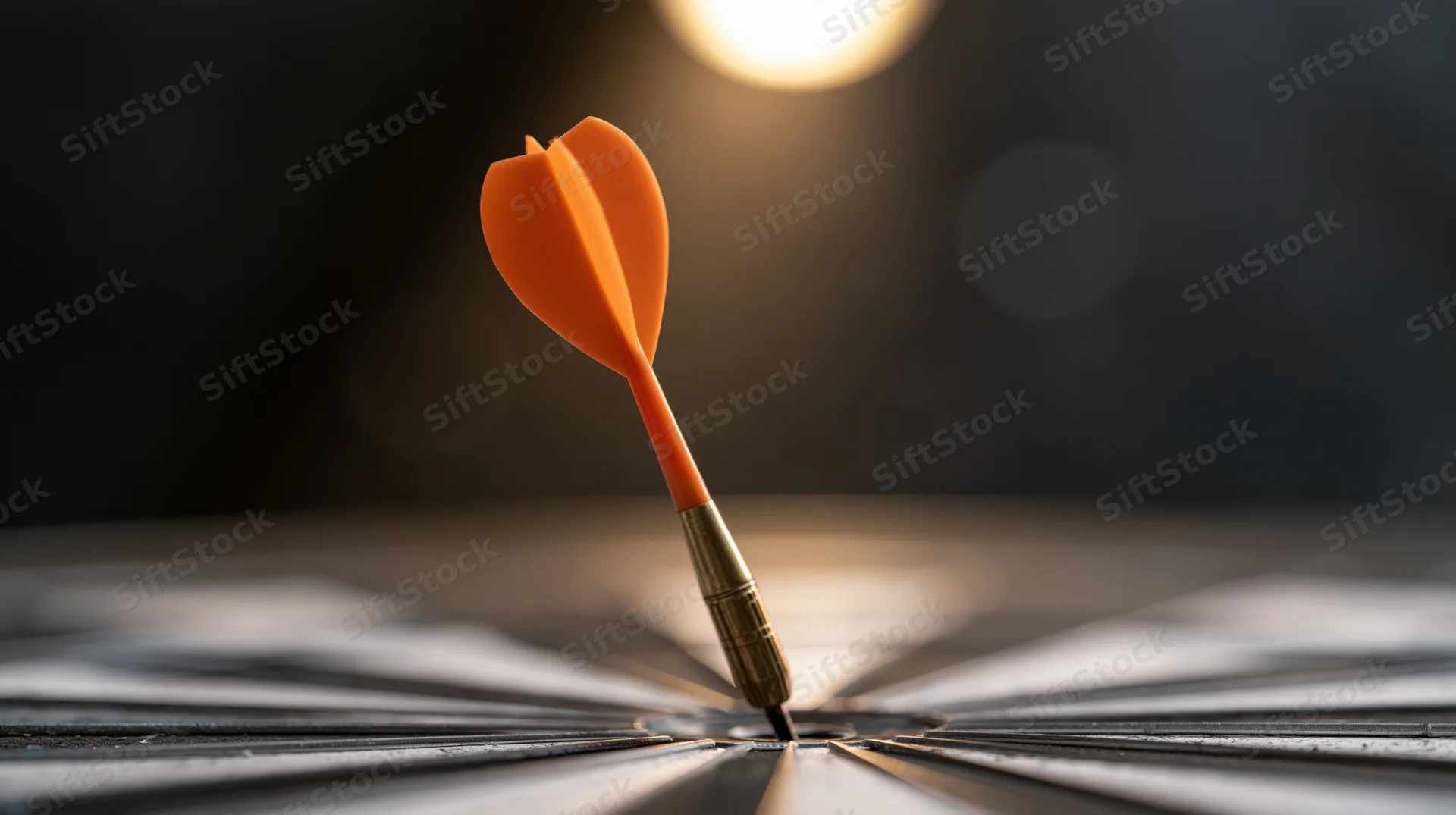 Orange dart stuck dead-center in a black target board