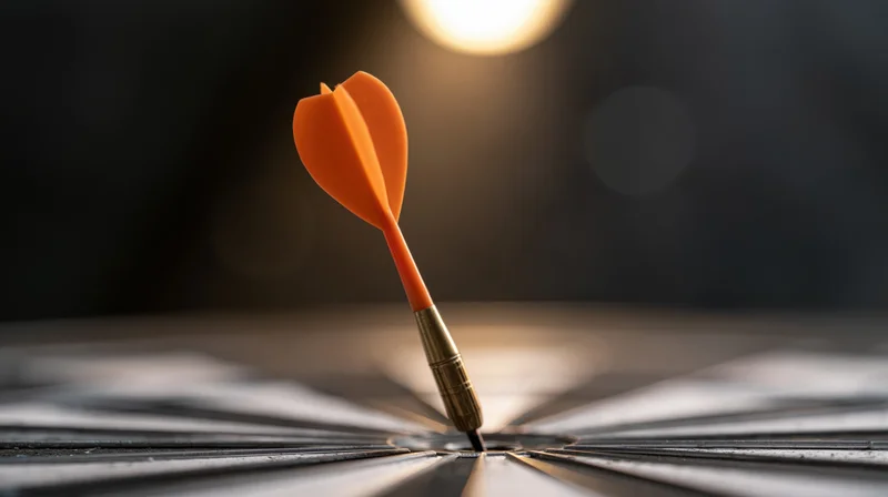 Orange dart stuck dead-center in a black target board