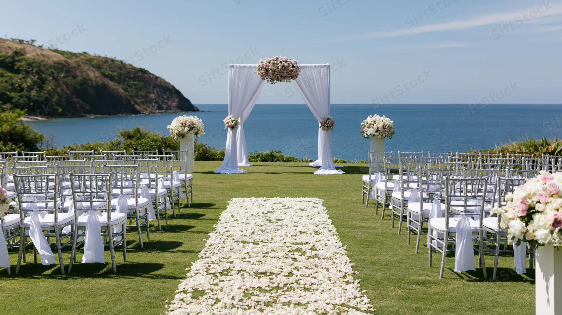 Wedding ceremony setup on a manicured lawn with floral aisle and ocean view