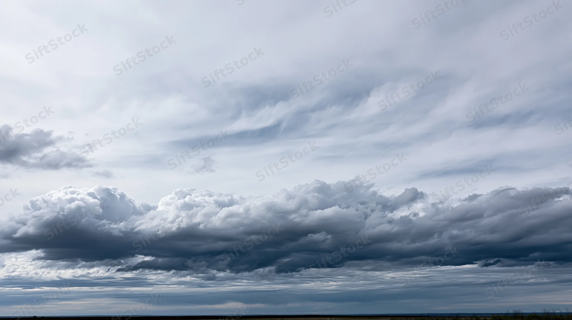 Large billowing cumulus clouds filling the sky above a distant horizon