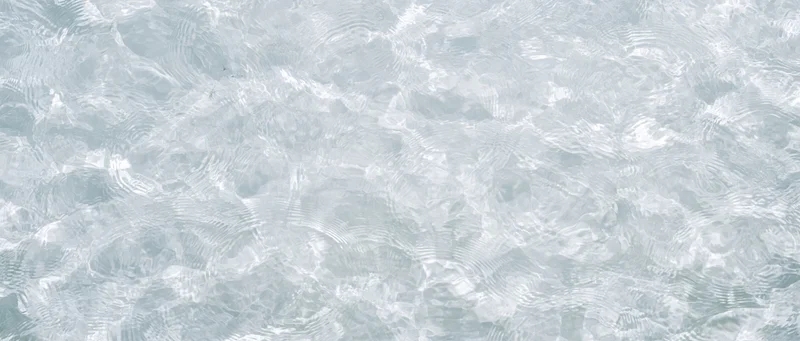 Overhead view of clear shallow water surface with ripples and light reflections