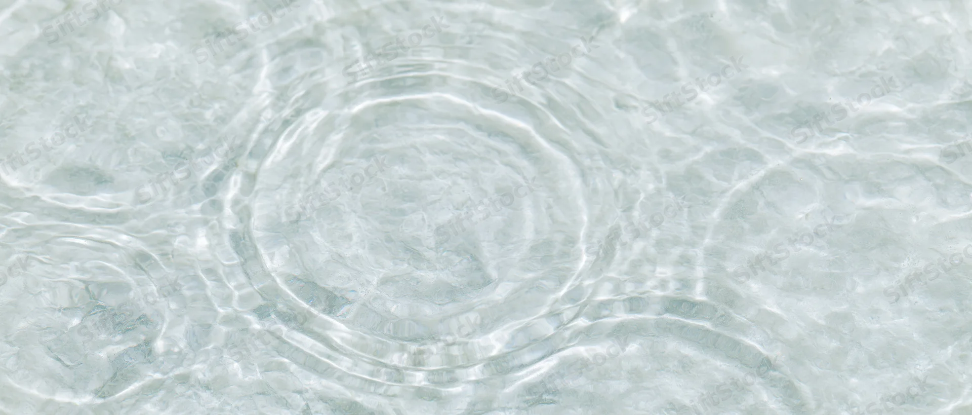 Overhead closeup of clear shallow water surface with ripples and light reflections