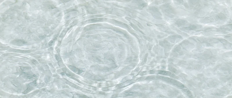 Overhead closeup of clear shallow water surface with ripples and light reflections