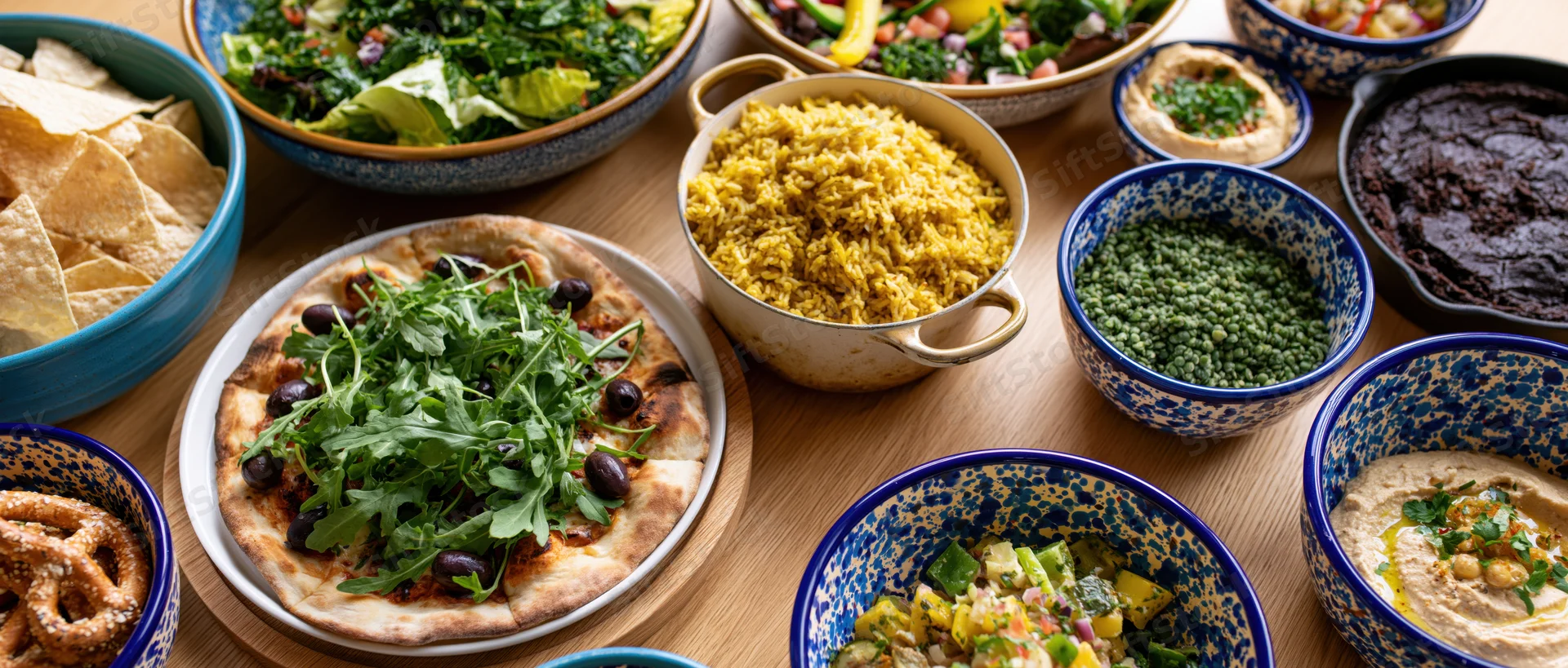 Overhead view of a shared meal with various dishes arranged on a wooden table