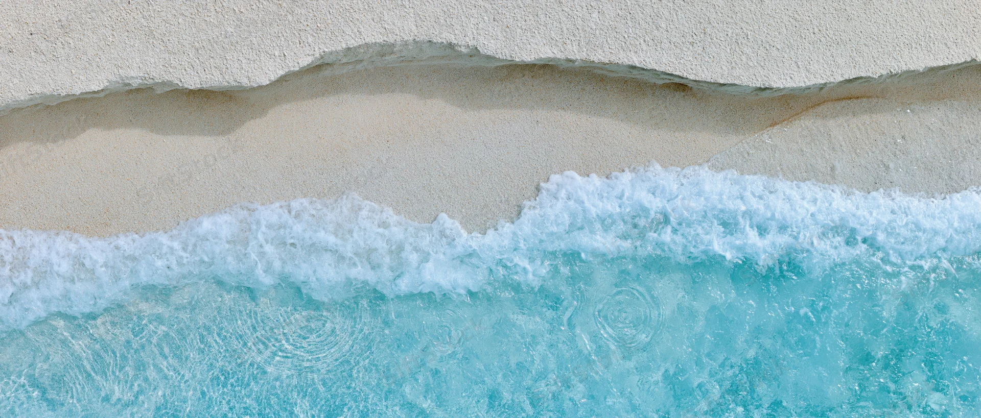 Overhead view of waves breaking on a sandy beach shoreline