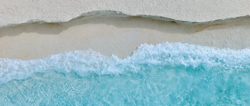 Overhead view of waves breaking on a sandy beach shoreline