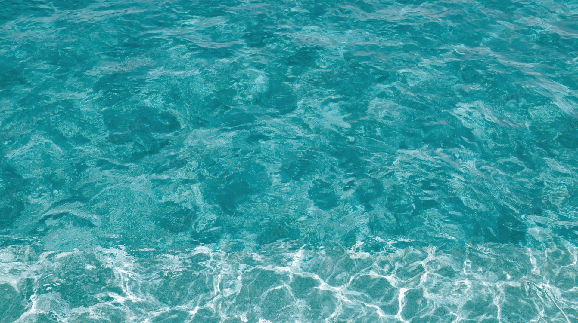 Overhead view of gently rippling clear turquoise swimming pool water surface