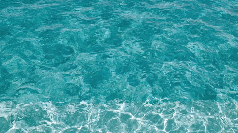 Overhead view of gently rippling clear turquoise swimming pool water surface
