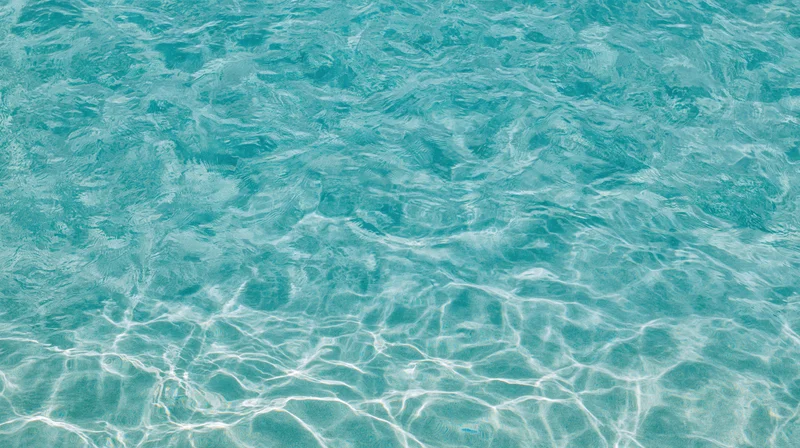 Overhead view of gently rippling swimming pool water surface with light reflections