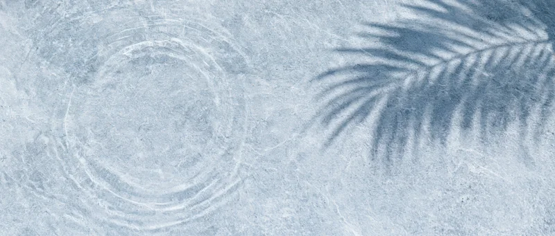 Shallow clear water with ripples and palm leaf shadow on textured surface