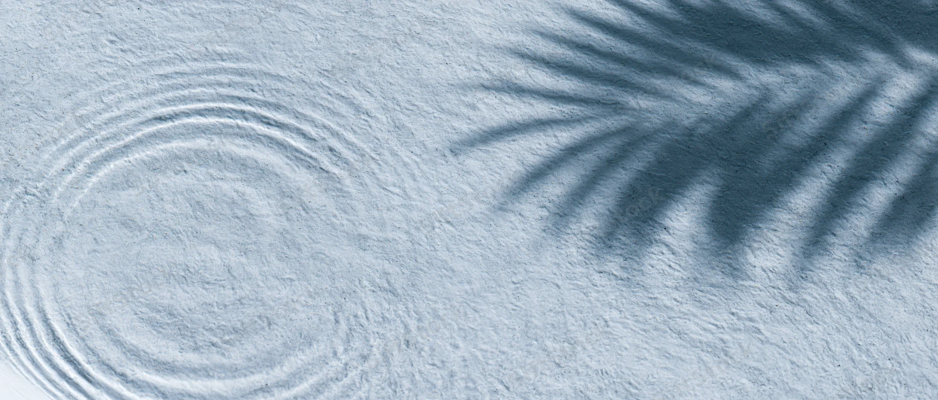 Shallow clear water with ripples and palm leaf shadow on textured surface