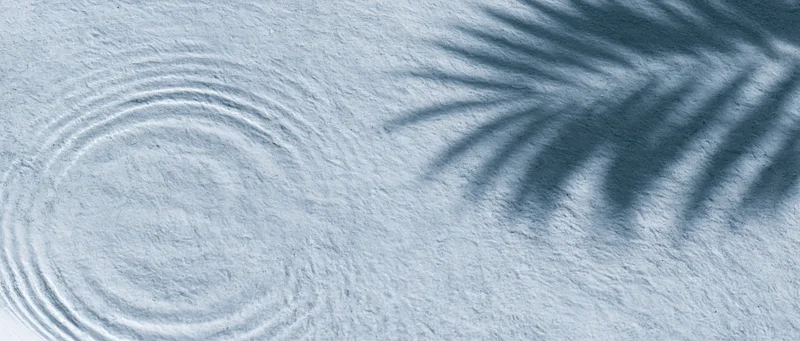 Shallow clear water with ripples and palm leaf shadow on textured surface