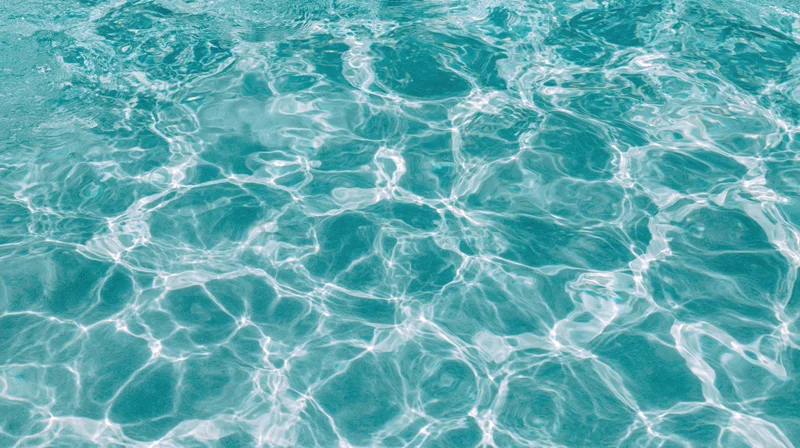 Overhead view of swimming pool water surface with light ripples and reflections