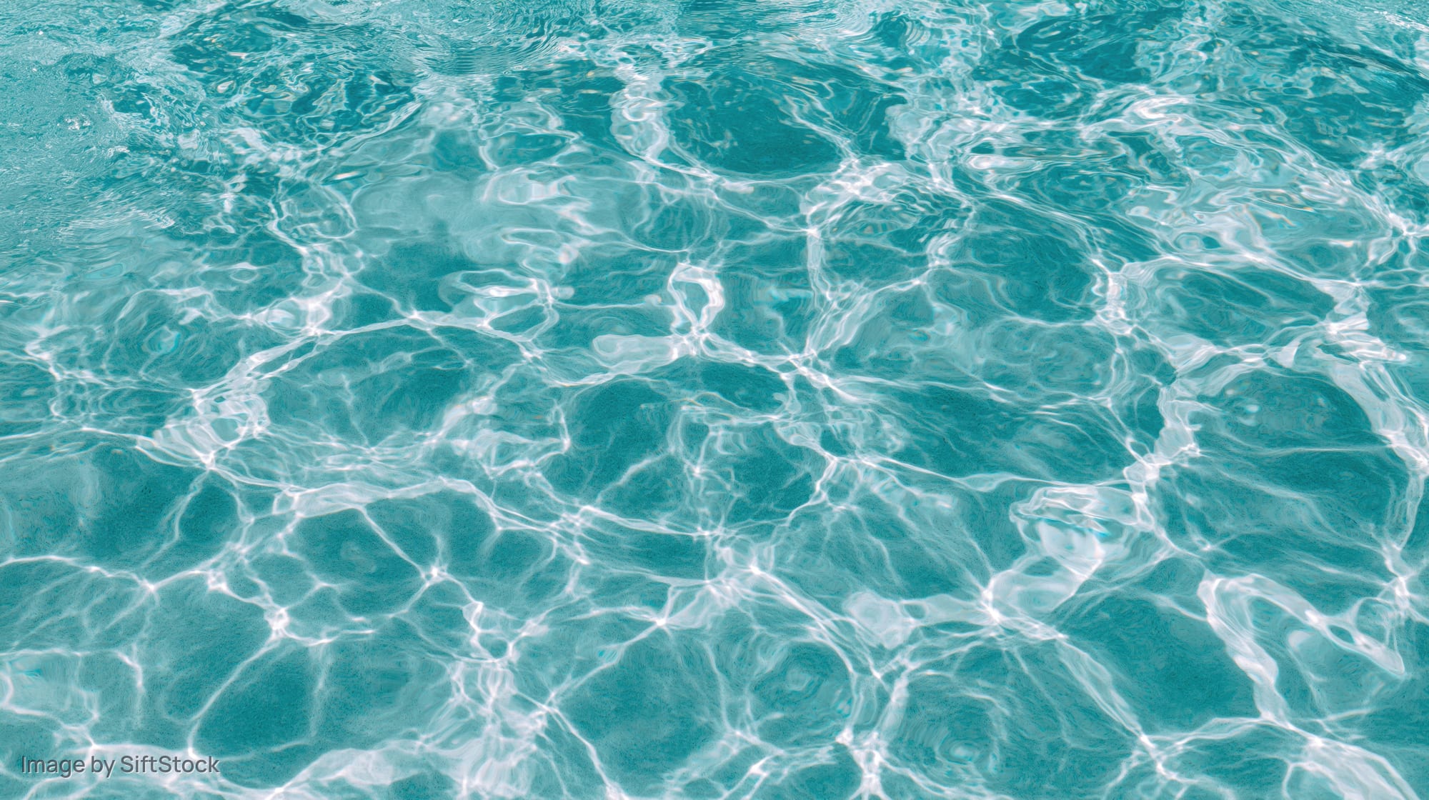 Overhead view of swimming pool water surface with light ripples and reflections