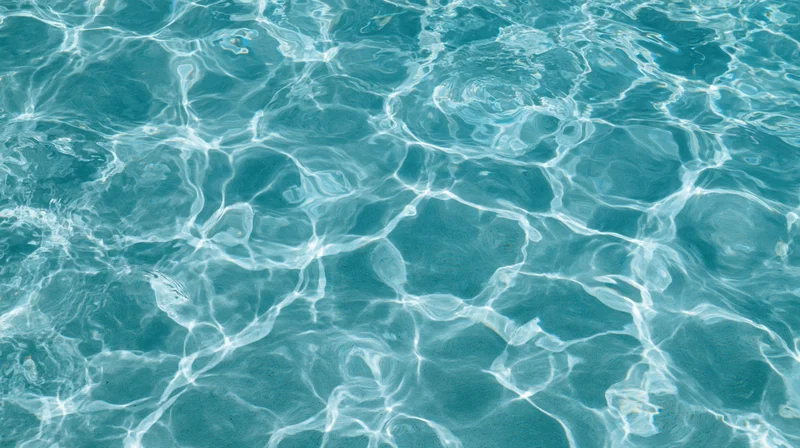 Overhead view of swimming pool water surface with ripples and light reflections