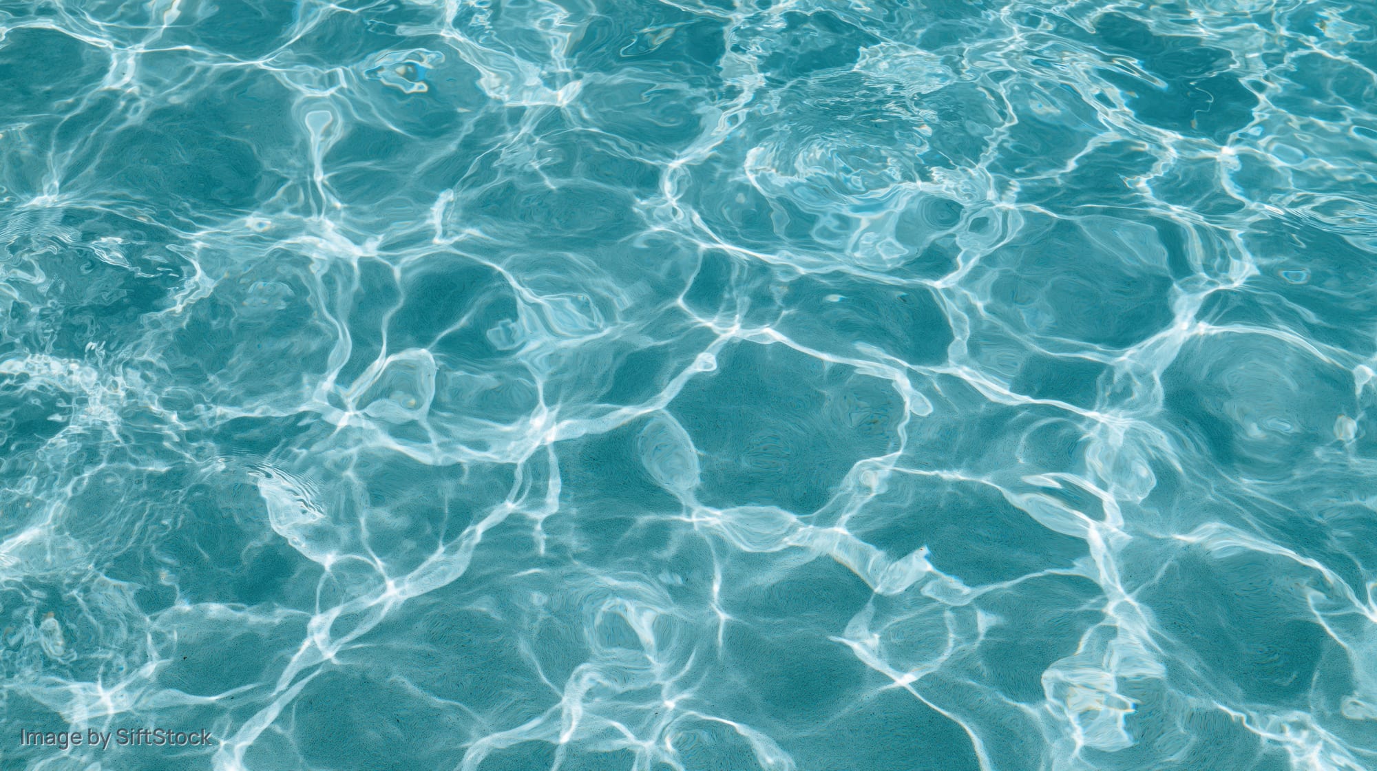 Overhead view of swimming pool water surface with ripples and light reflections