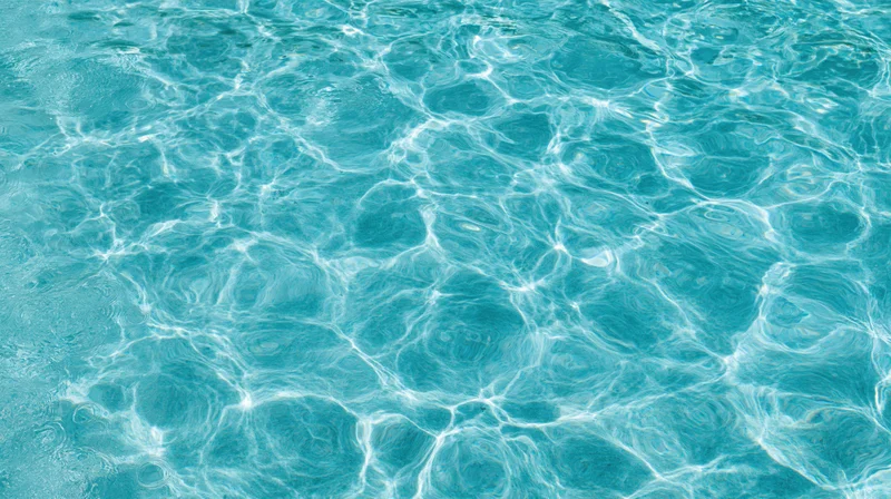 Overhead view of swimming pool water surface with ripples and light reflections