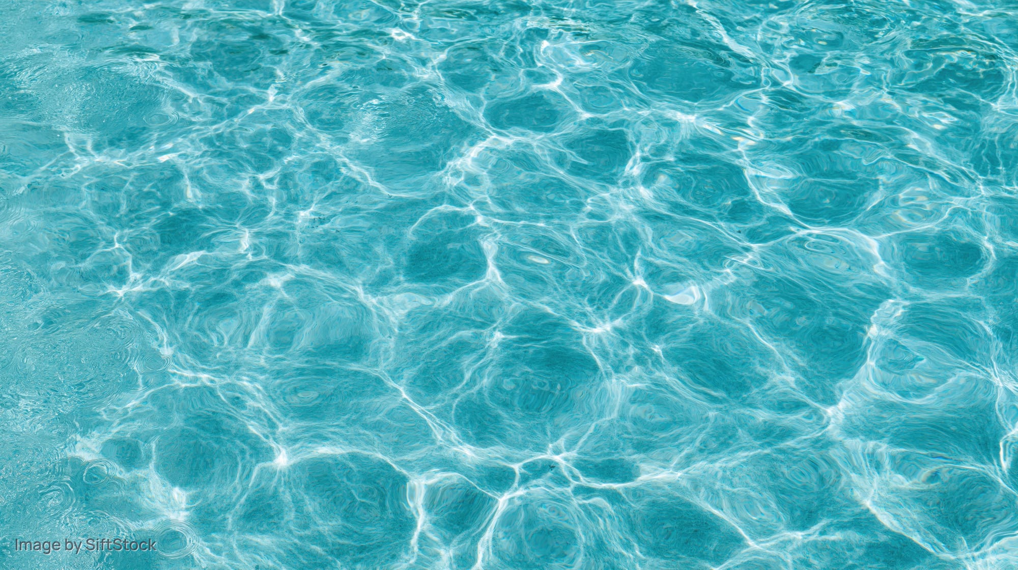 Overhead view of swimming pool water surface with ripples and light reflections