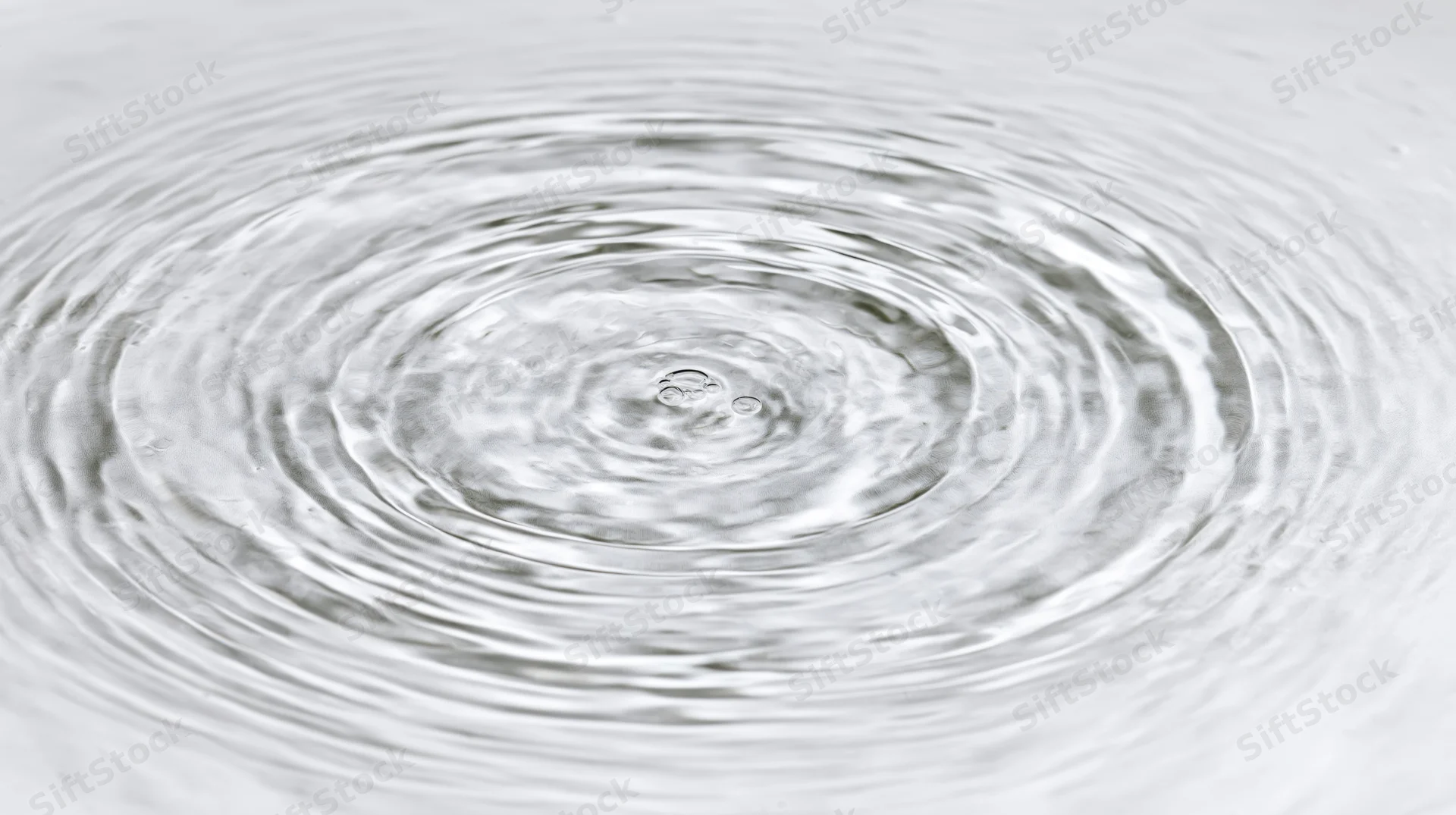 Overhead view of concentric ripples spreading across a calm water surface