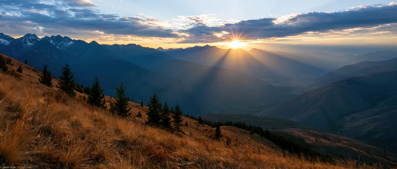 Panoramic alpine landscape at golden hour sunset with sun rays over mountain valley and grassy ridge