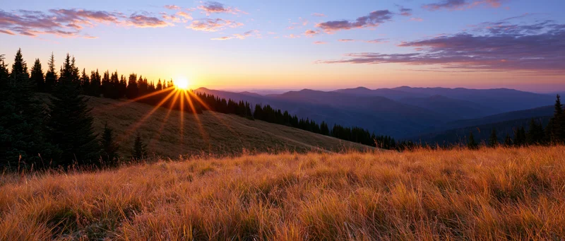 Golden sunset over mountain meadow with sunburst and distant hills