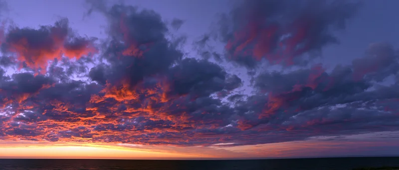 Panoramic ocean sunset with dramatic cumulus clouds filling the sky at twilight