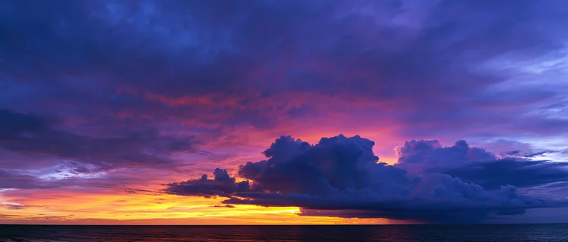 Panoramic ocean sunset with dramatic cumulus clouds at twilight