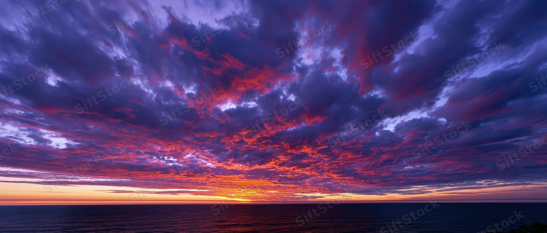 Panoramic ocean sunset with dramatic cumulus clouds filling the sky at twilight