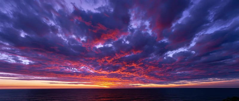 Panoramic ocean sunset with dramatic cumulus clouds filling the sky at twilight