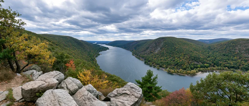Panoramic view of a wide river valley surrounded by forested hills in autumn