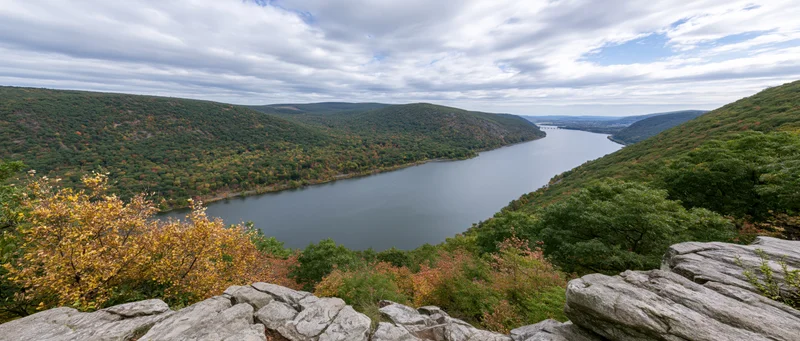 Panoramic view of a wide river cutting through a forested valley from a rocky overlook