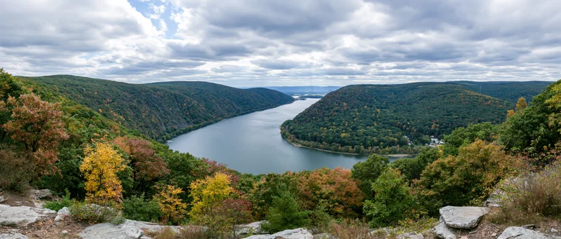 Panoramic view of a wide river valley surrounded by forested hills in autumn