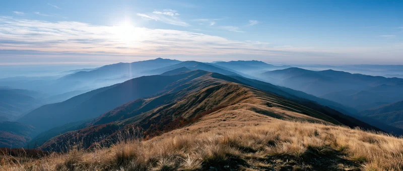 Panoramic view from mountain summit overlooking layered ridges and valleys at sunrise