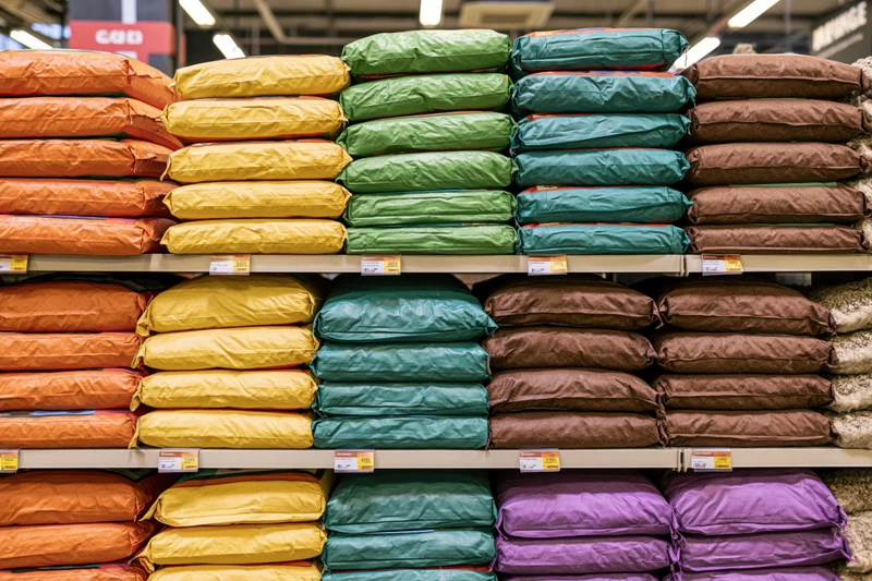 Stacked colorful bags of dry cat food on shelves in a retail store aisle