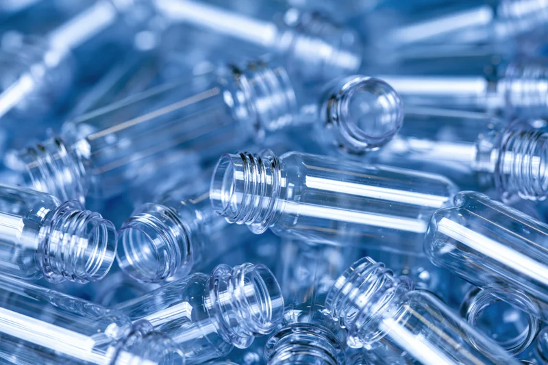 Clear plastic bottle preforms piled together in a heap