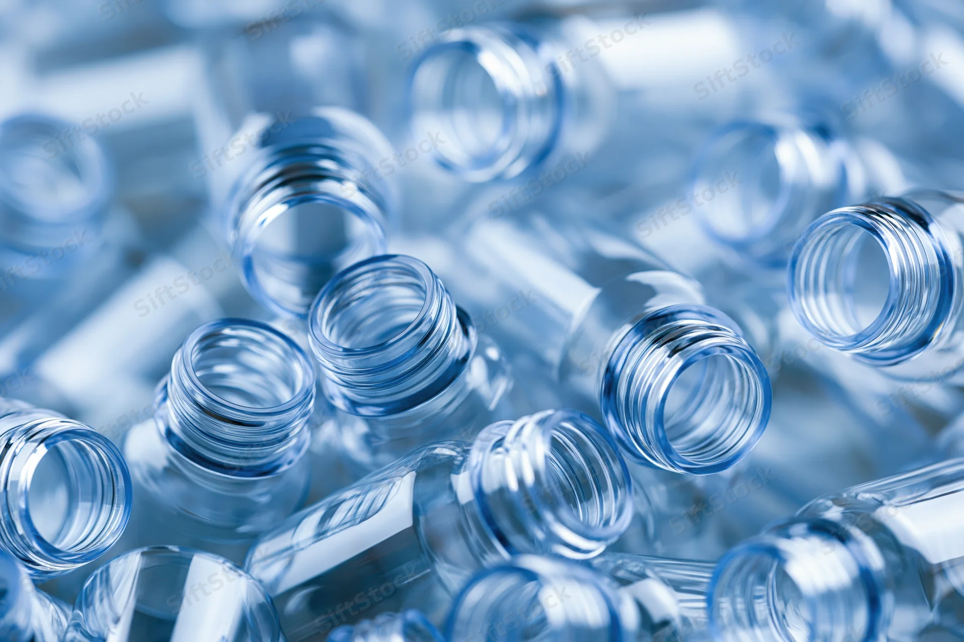 Clear plastic bottle preforms scattered in a heap