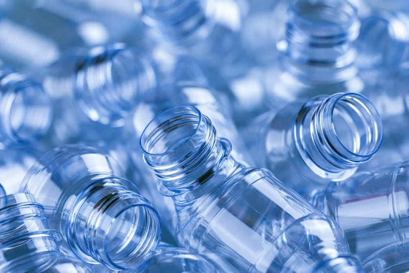 Clear plastic bottle preforms piled together in a heap