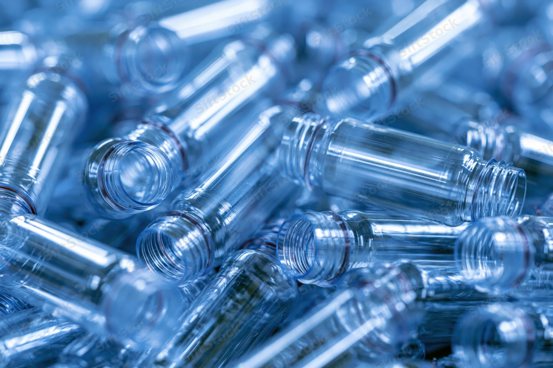 Heap of clear plastic bottle preforms scattered in industrial setting