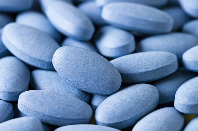 Close-up of oval blue coated tablets piled together filling the frame