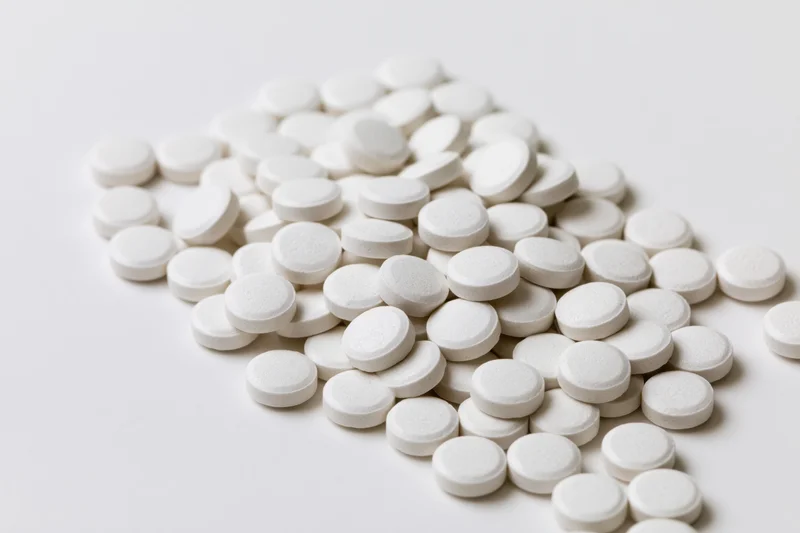 Scattered white round tablets piled on a plain white surface